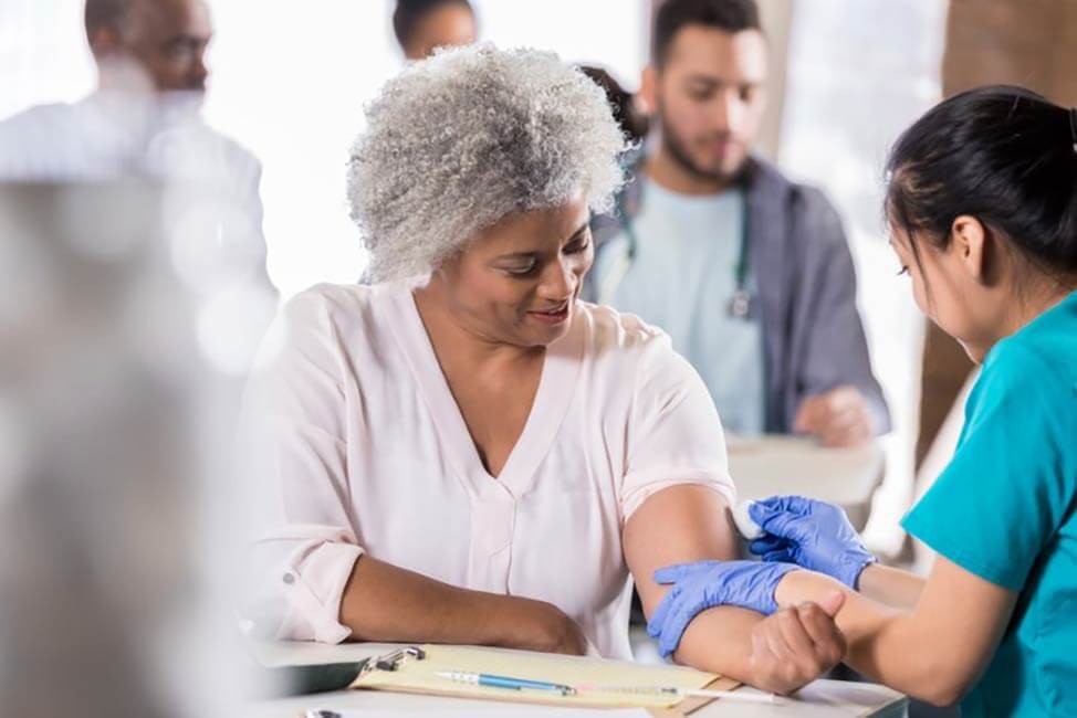 caregiver giving an elderly lady a flu shot