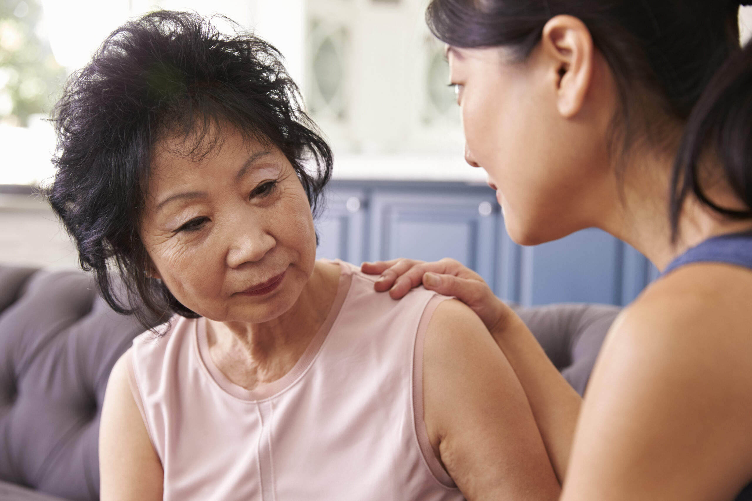 Depressed senior woman being comforted by her daughter.