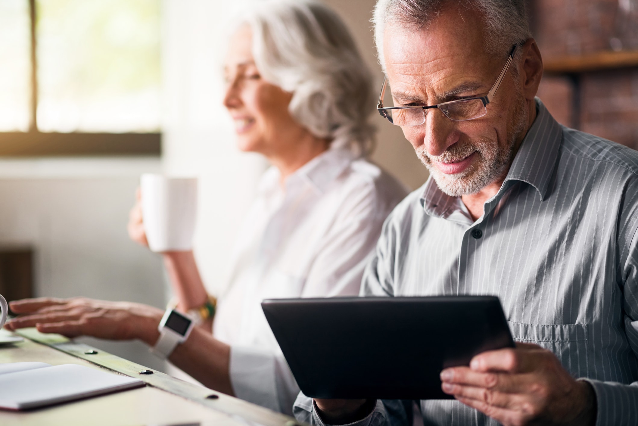 A senior man is using his tablet to check his place on the senior living waitlist.