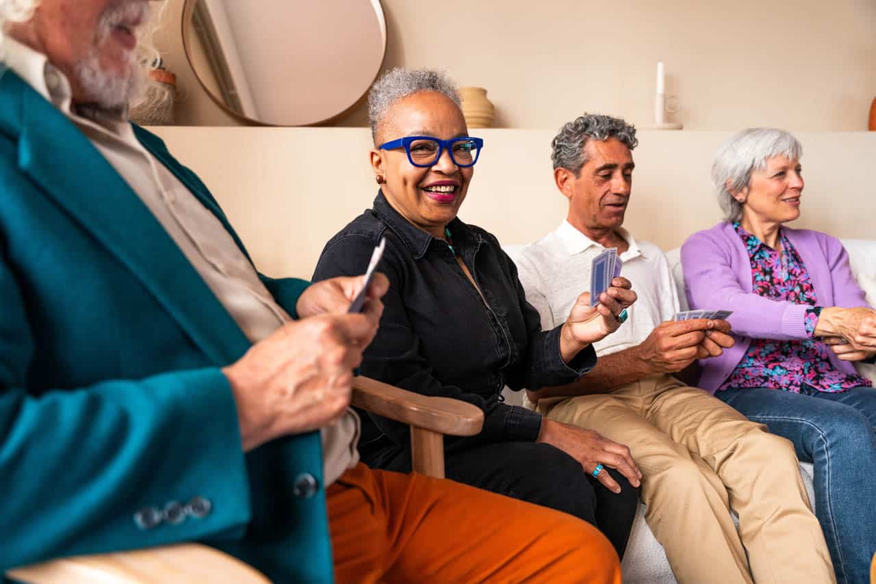 Group of happy senior friends bonding at home for dinner party - Cheerful and youthful old mature multiethnic people having fun